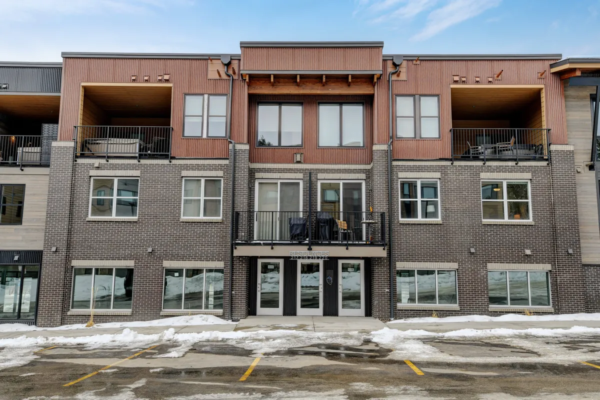 The exterior of the building features double doors, inviting balconies with seating, and expansive windows. The scene suggests easy access to local entertainment and community events, while the balconies hint at the vibrant social atmosphere and connectivity to the neighborhood.