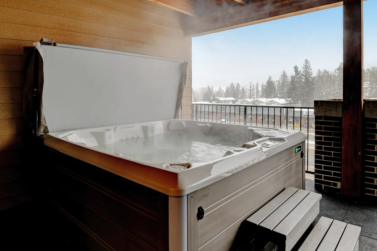 A scenic view of a private hot tub on a balcony with a backdrop of mountains. The inviting hot tub is perfect for relaxing and socializing after a night out, or for memorable evenings in with friends.