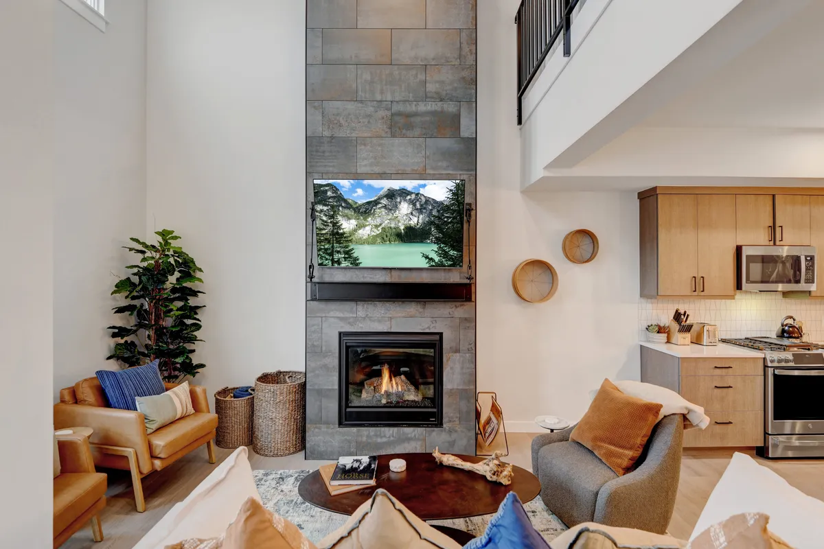 A warm and welcoming living space with a stone-clad fireplace, a flat-screen TV displaying a nature scene, plush seating, and a coffee table, all set in an inviting layout ideal for movie nights or gaming.