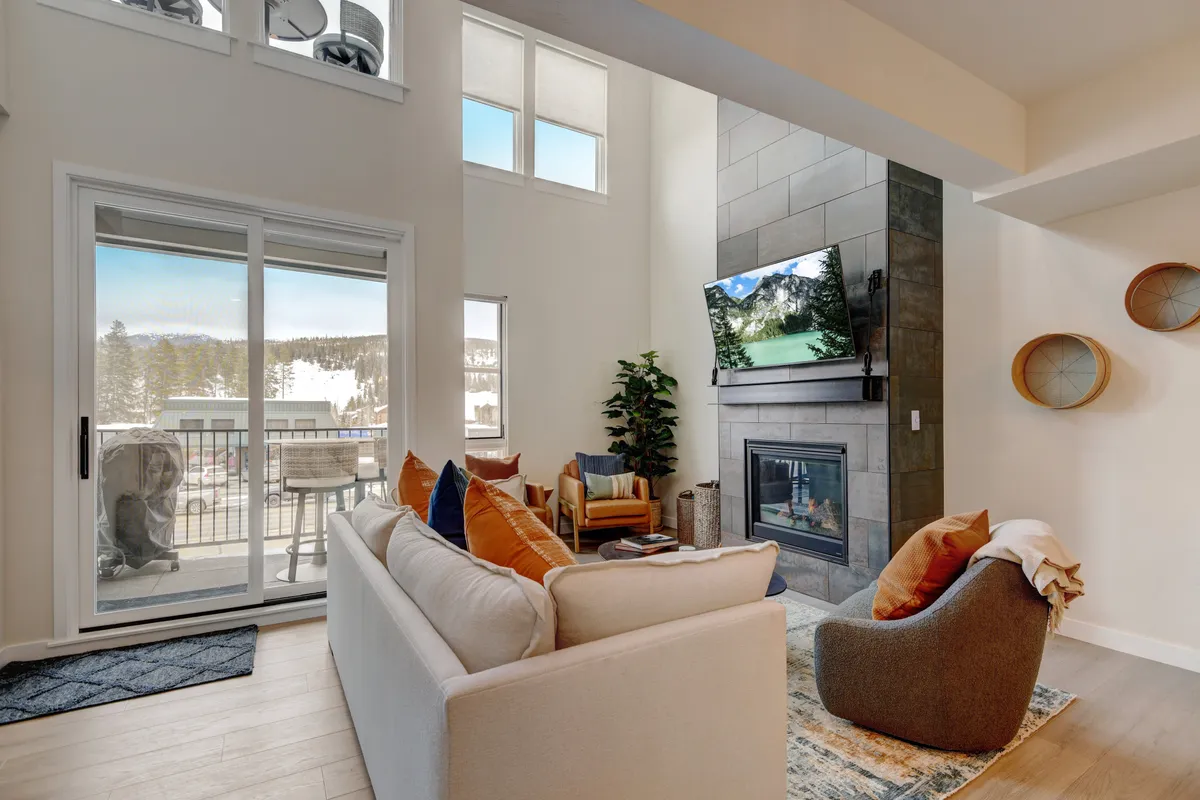 A cozy and contemporary living room featuring large windows that frame beautiful mountain views, a modern fireplace for warmth, and a comfortable seating area arranged for conversation and relaxation.