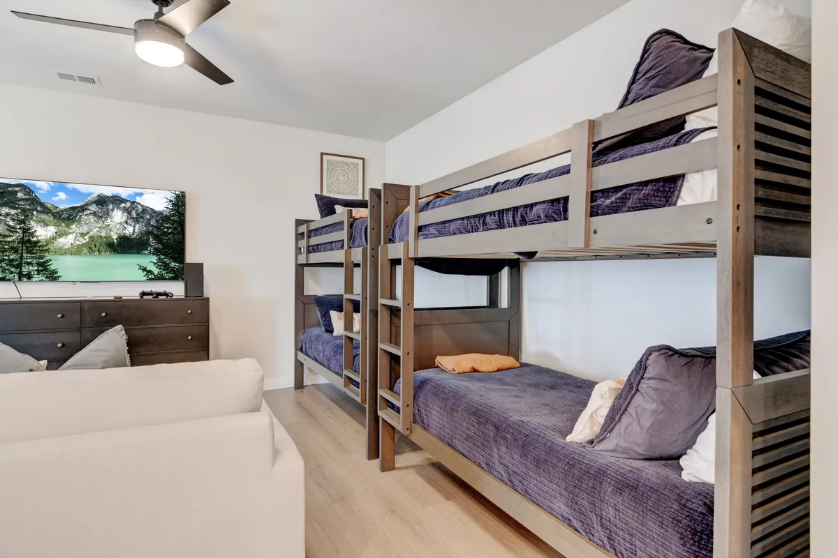 A playful bunk room featuring twin-over-twin bunk beds, a television, and a comfortable sofa. The space exudes fun and relaxation, with ample room for kids or friends to unwind and enjoy group activities.