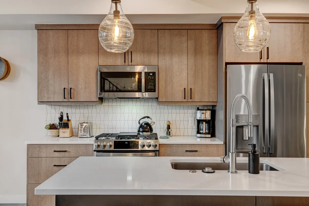 A modern kitchen with a large island, stainless steel appliances, and geometric tile backsplash, designed for both gourmet cooking and social gatherings. The inviting setup hints at the possibility of hosting a private chef or enjoying memorable dinners with friends and family.